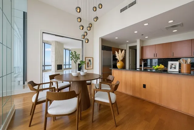 a kitchen with stainless steel appliances kitchen island granite countertop a dining table chairs and a refrigerator