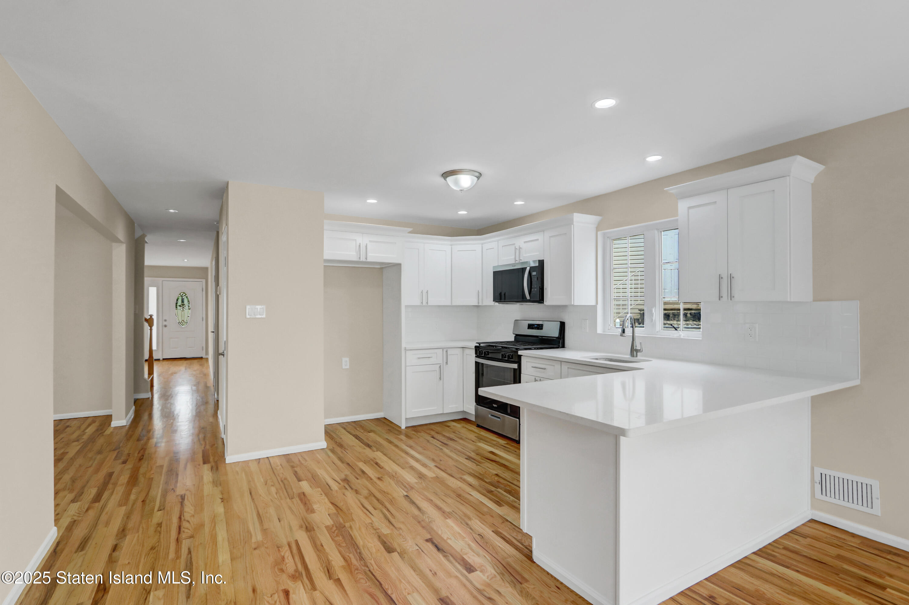 103 Savo Loop Staten Island, NY 10309 - Photo 21 of 46 a kitchen with stainless steel appliances a sink a stove a refrigerator cabinets and a wooden floor