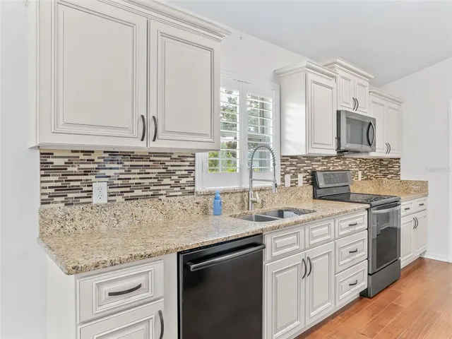 a kitchen with stainless steel appliances granite countertop white cabinets stove a sink and dishwasher