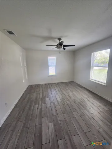 a view of empty room with wooden floor and fan