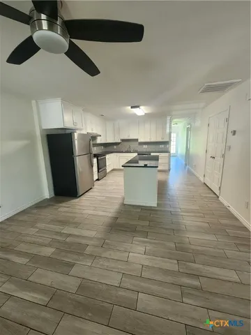 a view of a kitchen with kitchen island a counter top space a sink and stainless steel appliances
