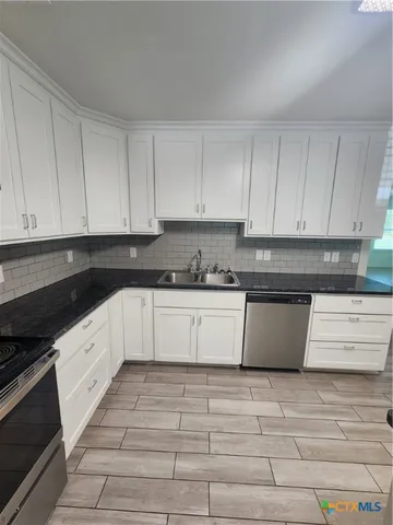 a large white kitchen with granite countertop white cabinets
