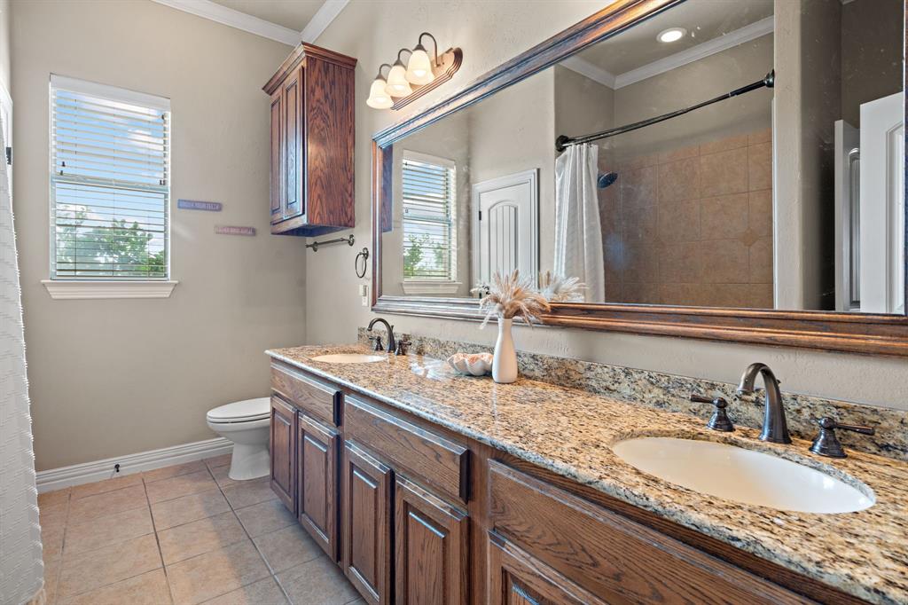 1341 Maxwell Road Haslet, TX 76052 - Photo 31 of 40 a bathroom with a granite countertop double vanity sink a mirror and a toilet
