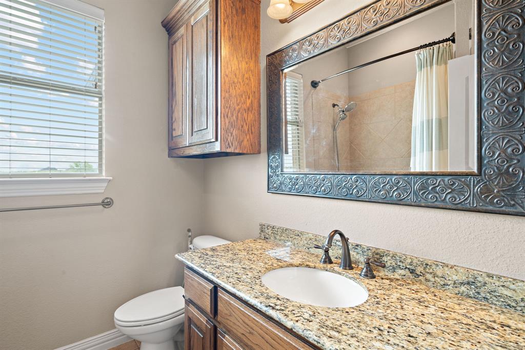 1341 Maxwell Road Haslet, TX 76052 - Photo 35 of 40 a bathroom with a granite countertop sink a toilet and a mirror