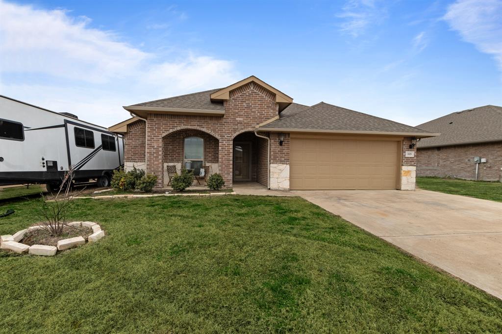 View of front of home featuring a garage, brick siding, a shingled roof, and a front lawn
