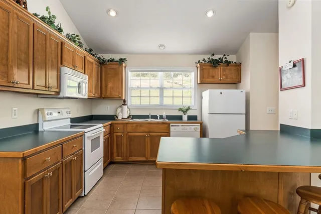 a kitchen with stainless steel appliances granite countertop a refrigerator sink stove and white cabinets