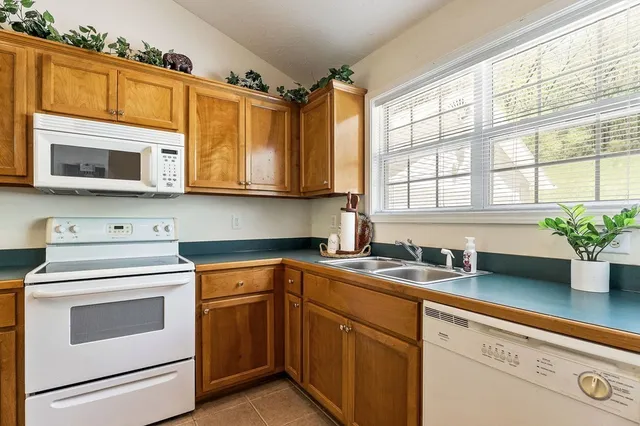 a kitchen with stainless steel appliances granite countertop white cabinets a microwave oven and a potted plant