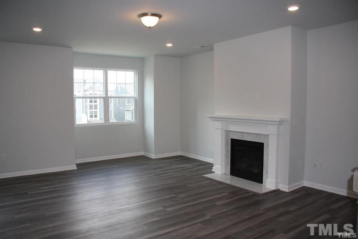 2919 Sunflower Road Apex, NC 27502 - Photo 11 of 34 an empty room with wooden floor fireplace and windows