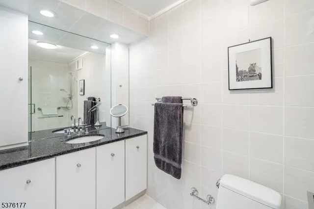 a bathroom with a granite countertop sink a mirror and shower