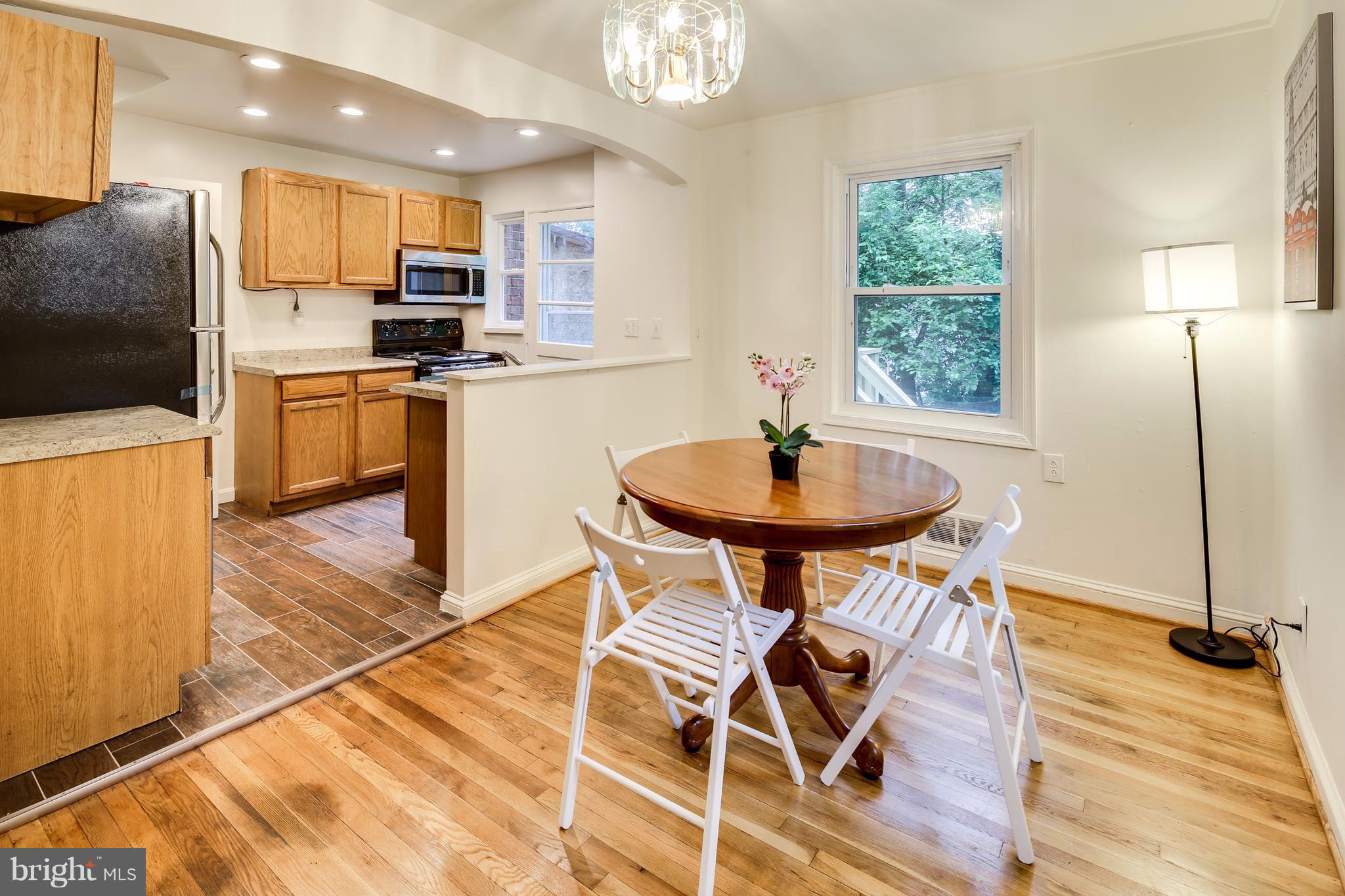 12025 Berry Street Silver Spring, MD 20902 - Photo 4 of 19 a kitchen with stainless steel appliances a dining table chairs and wooden floor