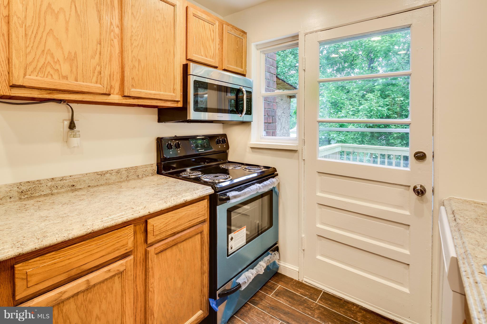 12025 Berry Street Silver Spring, MD 20902 - Photo 6 of 19 a kitchen with granite countertop a stove and a microwave