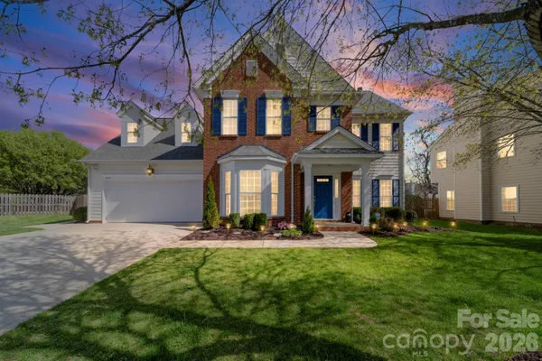 a front view of a house with lots of trees and plants