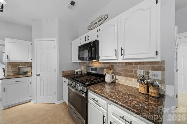 a kitchen with granite countertop white cabinets and stainless steel appliances