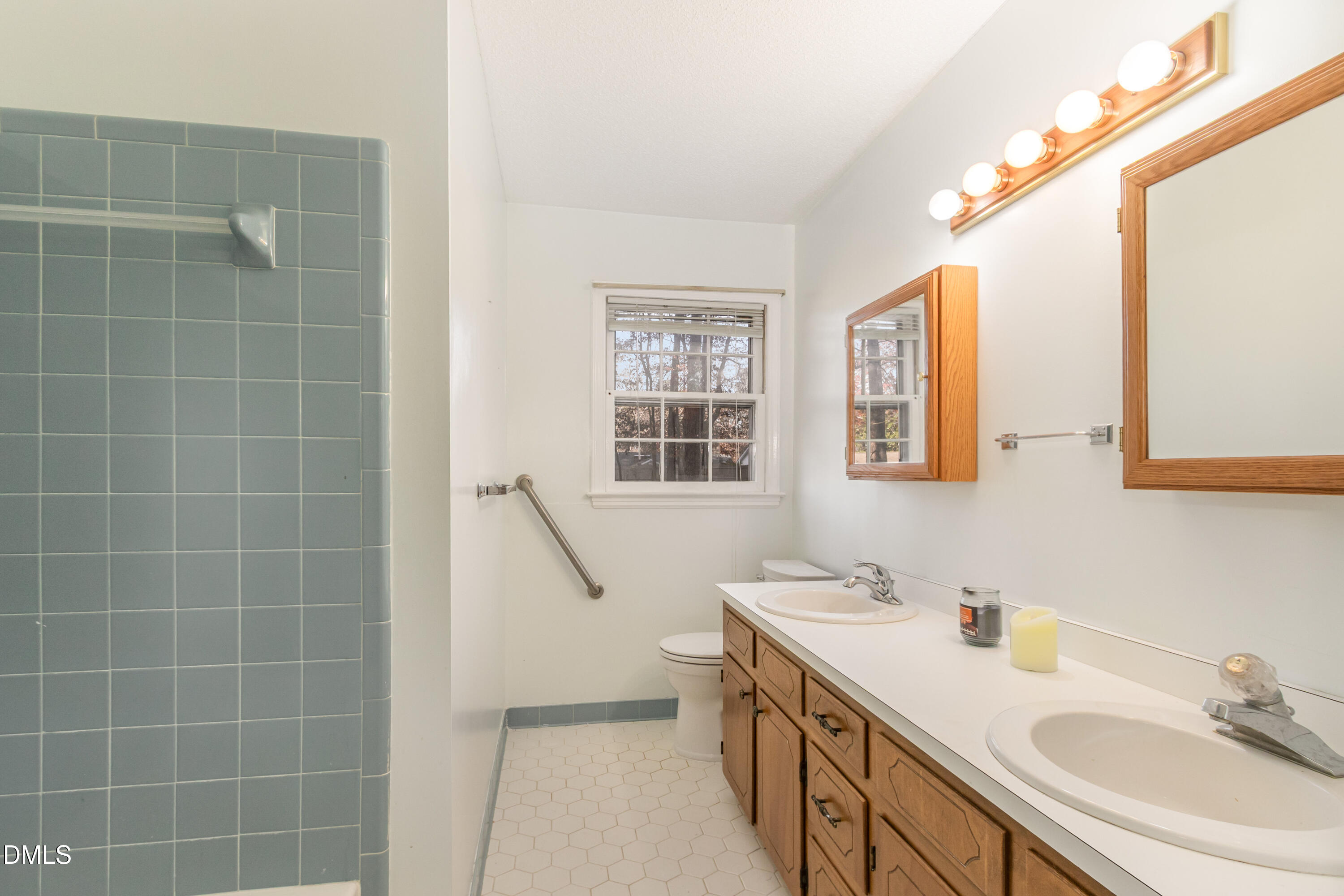 6800 Valley Drive Raleigh, NC 27612 - Photo 21 of 35 a bathroom with a double vanity sink a mirror and a shower