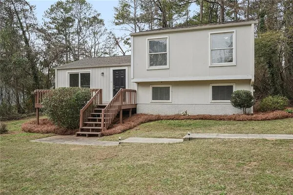 a view of a house with backyard and a tree