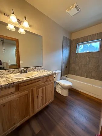 a bathroom with a granite countertop sink a toilet and bathtub