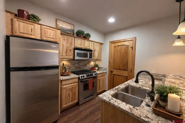 a kitchen with granite countertop a refrigerator stove and sink