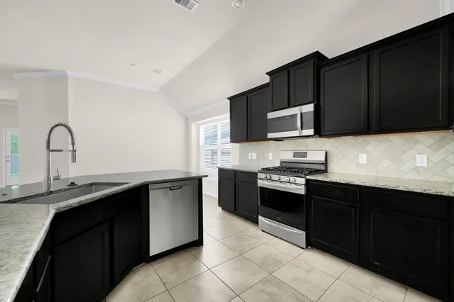 a kitchen with stainless steel appliances granite countertop a sink stove and microwave