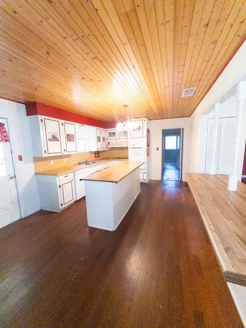 613 Laurel Road Athens, TX 75751 - Photo 5 of 13 Kitchen featuring a wood plank ceiling, white cabinetry with red trim, wood-finish countertops, a central island, and dark wood-finish flooring