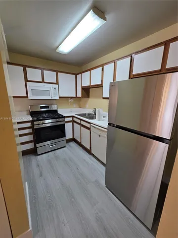 a kitchen with a refrigerator and a stove top oven