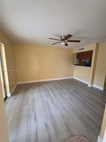 an empty room with wooden floor and a ceiling fan