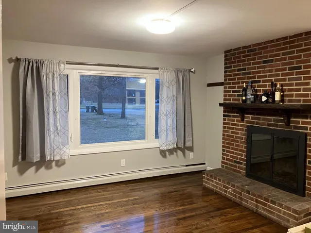 a view of an empty room with wooden floor and a fireplace