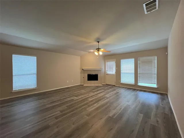 an empty room with wooden floor chandelier and windows