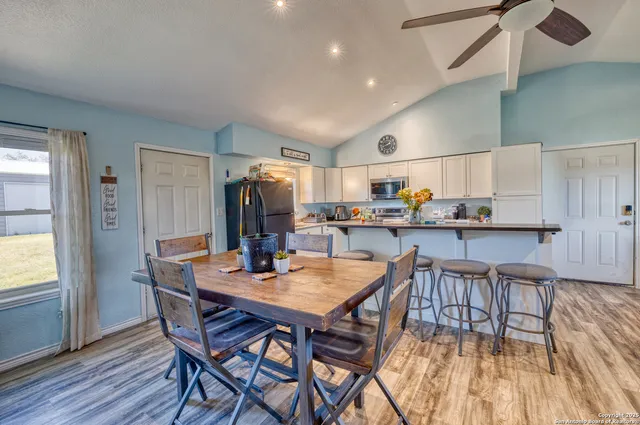 a dining room with stainless steel appliances kitchen island granite countertop a dining table and chairs