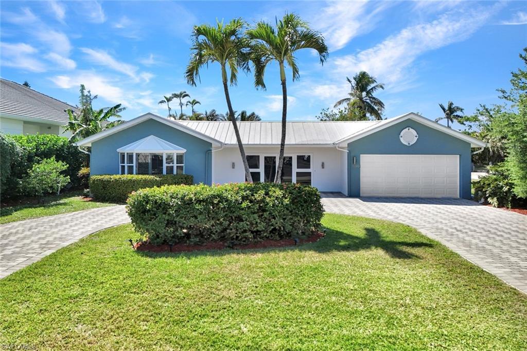 1550 Sandpiper Street Naples, FL 34102 - Photo 3 of 34 a front view of a house with a garden