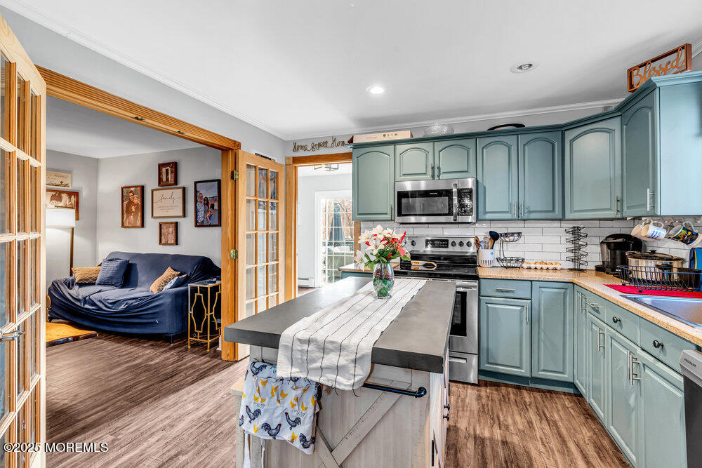 235 Perrineville Road Jackson, NJ 08527 - Photo 8 of 20 a kitchen with stainless steel appliances granite countertop a stove top oven a sink dishwasher a dining table and chairs with wooden floor
