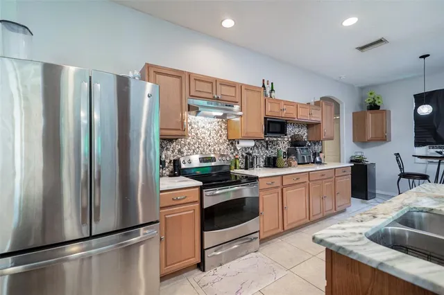 a kitchen with stainless steel appliances granite countertop a refrigerator sink and stove