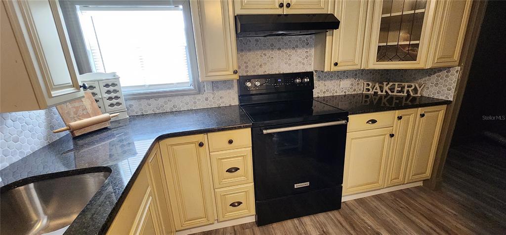 19865 Southwest 5th Place Dunnellon, FL 34431 - Photo 40 of 78 a kitchen with granite countertop a refrigerator a stove and a sink with wooden floor