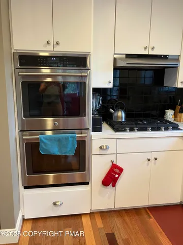 a kitchen with a stove a sink dishwasher and a dining table with wooden floor
