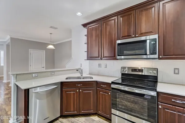 a kitchen with granite countertop a sink dishwasher stove and microwave with wooden cabinets