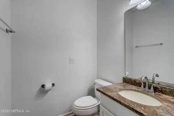 a bathroom with a granite countertop toilet a sink and mirror