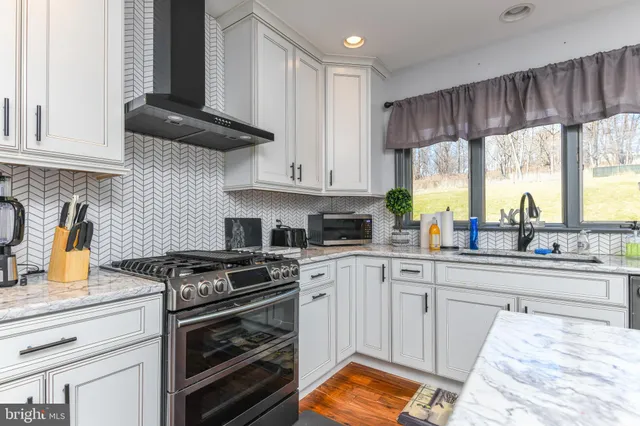 a kitchen with stainless steel appliances granite countertop a stove a sink and a white cabinets