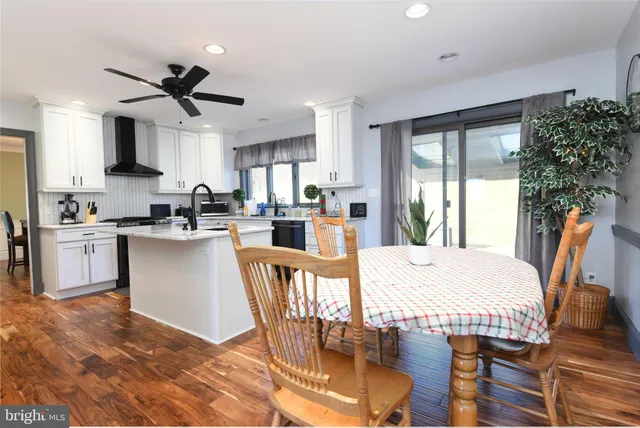 a kitchen with stainless steel appliances granite countertop a stove a sink a refrigerator dining table and chairs