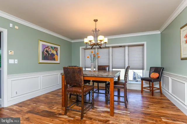 a dining room with wooden floor a chandelier a wooden table and chairs