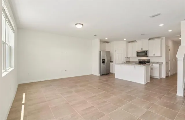 a view of kitchen with kitchen island stainless steel appliances refrigerator sink and cabinets