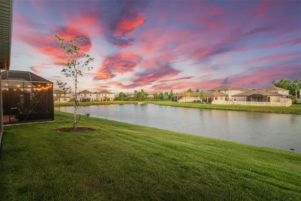 a kitchen with stainless steel appliances granite countertop a stove top oven a sink dishwasher a refrigerator and white cabinets with wooden floor