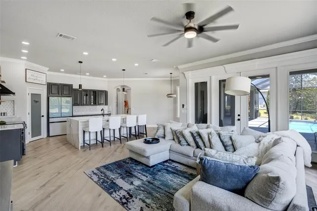 a living room with furniture kitchen view and a chandelier