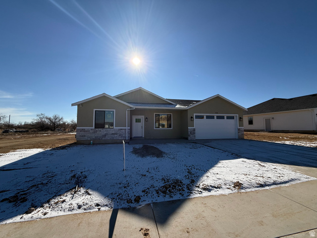 Ranch-style house featuring stone siding, stucco siding, driveway, and a garage
