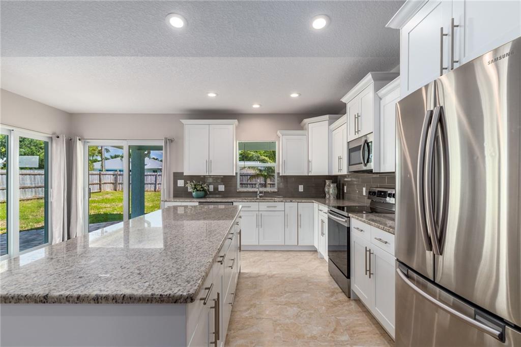 5111 Southeast Post Terrace Stuart, FL 34997 - Photo 6 of 34 a kitchen with stainless steel appliances granite countertop a refrigerator a sink a stove and oven