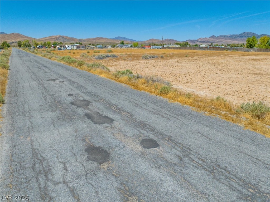 4610 Lawrence Road Pahrump, NV 89048 - Photo 17 of 42 A long, clear road stretches toward distant mountains, offering expansive desert views under a bright sky.