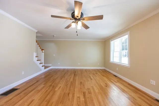 a view of an empty room with a window and wooden floor