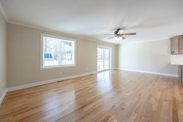 a view of an empty room with wooden floor and a window