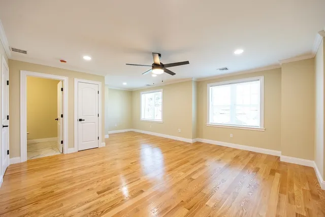 an empty room with wooden floor and ceiling fan