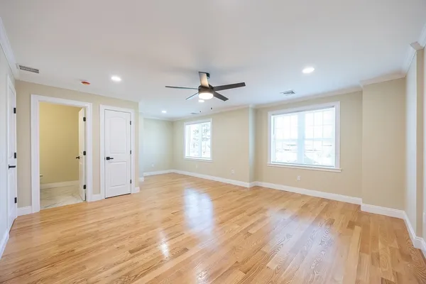 a view of an empty room with wooden floor and a window