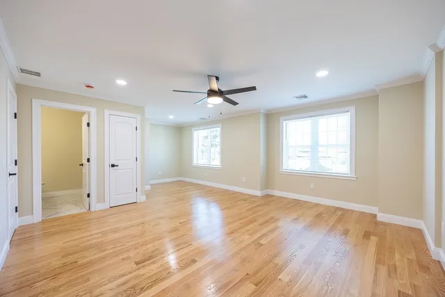 an empty room with wooden floor and ceiling fan