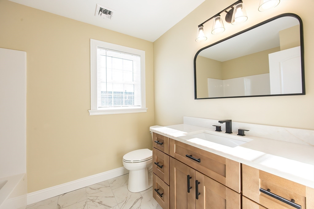 50 Pullman Avenue, Unit B Attleboro, MA 02703 - Photo 20 of 28 a bathroom with a toilet sink vanity and mirror
